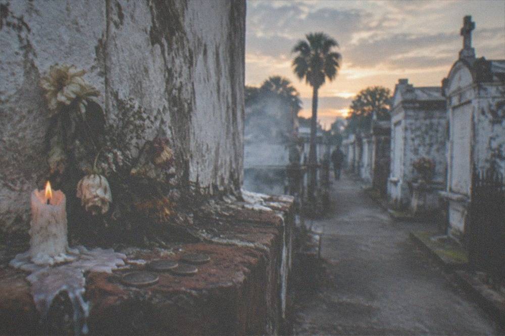 A candle and flowers left at the base of a weathered tomb in a New Orleans cemetery