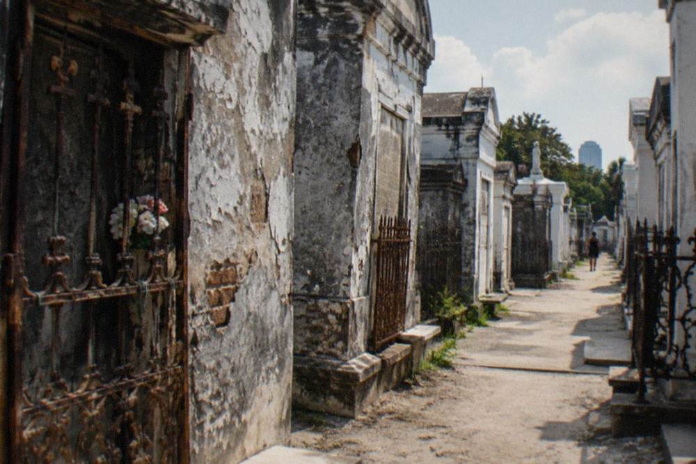 Weathered above-ground tombs packed closely together along a narrow walkway in a New Orleans cemetery