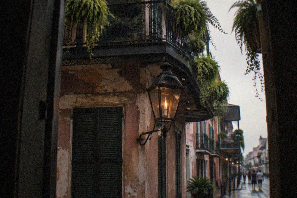 Iron balcony and gas-style lantern above a dark French Quarter street