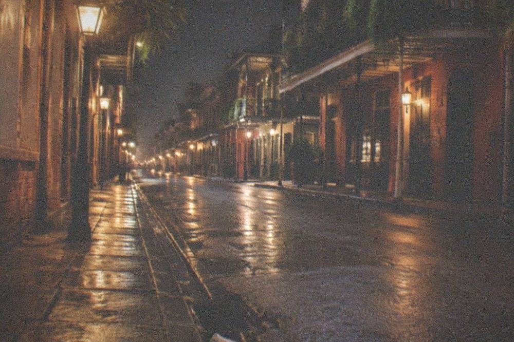 Empty French Quarter street at night with warm lamplight on old brick buildings