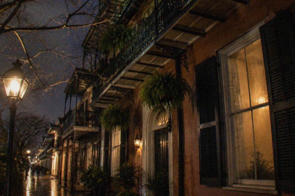 Iron-laced balconies of a Royal Street French Quarter townhouse seen from the sidewalk at night