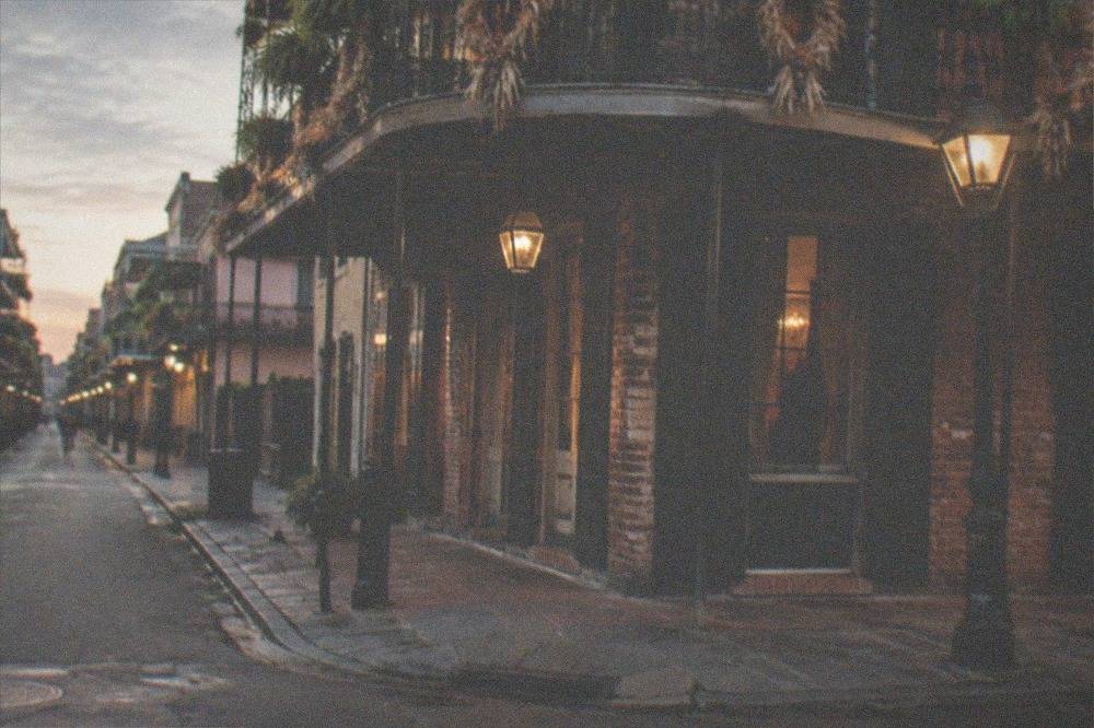 An evening street corner in the French Quarter with lantern light and fall decorations on iron balconies