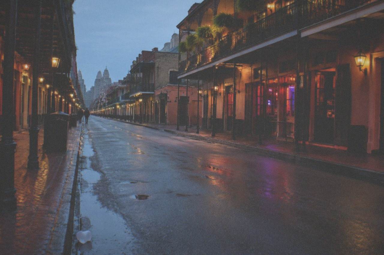 Bourbon Street at night with lit balconies and glowing bar signs along the empty morning street