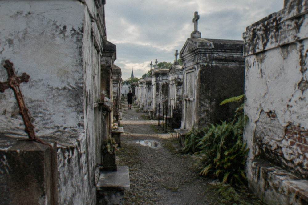 A narrow passage between leaning above-ground tombs in a historic New Orleans cemetery