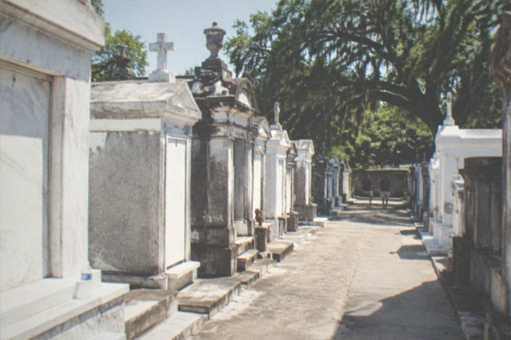 A wide view of rows of above-ground tombs under a bright sky in a New Orleans cemetery