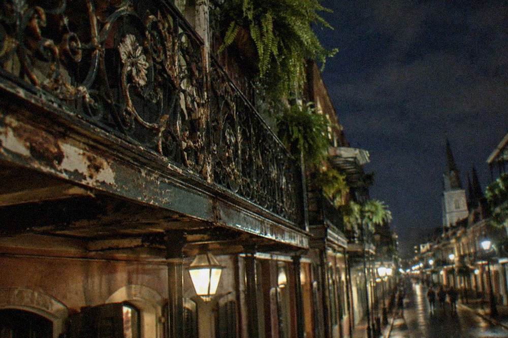 A close view of ornate wrought iron balcony railings on an old French Quarter building at night