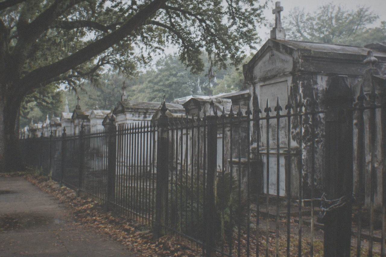 Rows of weathered above-ground tombs behind the iron gates of a Garden District cemetery