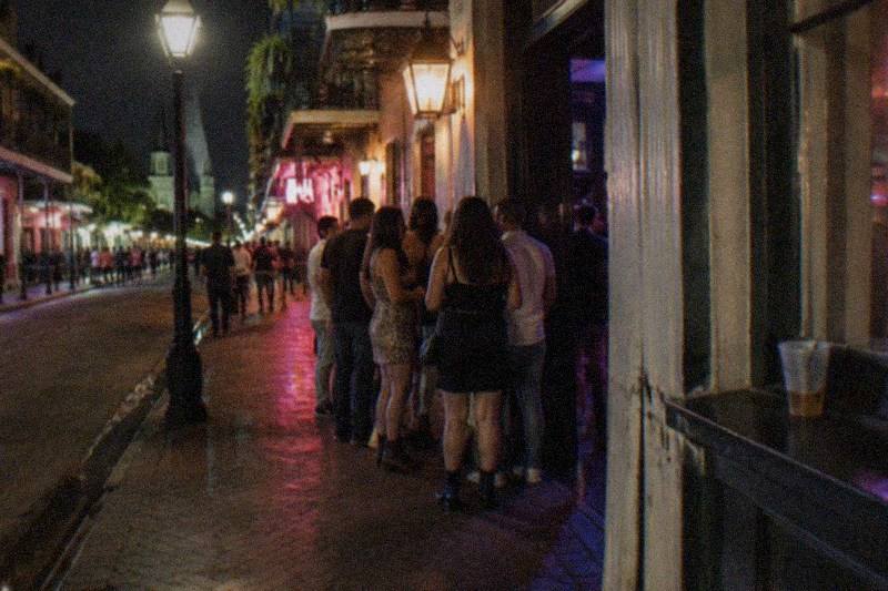 A haunted pub crawl group gathered at a lamplit French Quarter bar door