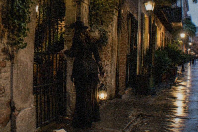 A guide leading a vampire-legend walking tour past a dark French Quarter courtyard at night
