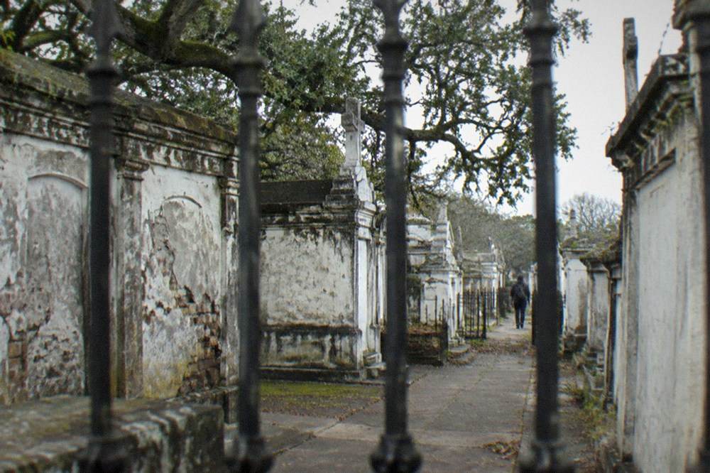 Rows of weathered above-ground tombs in a New Orleans cemetery with cracked plaster and iron gates