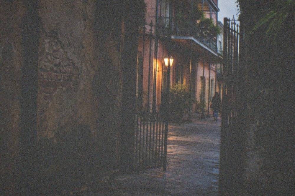 Dimly lit French Quarter alley with an old iron gate