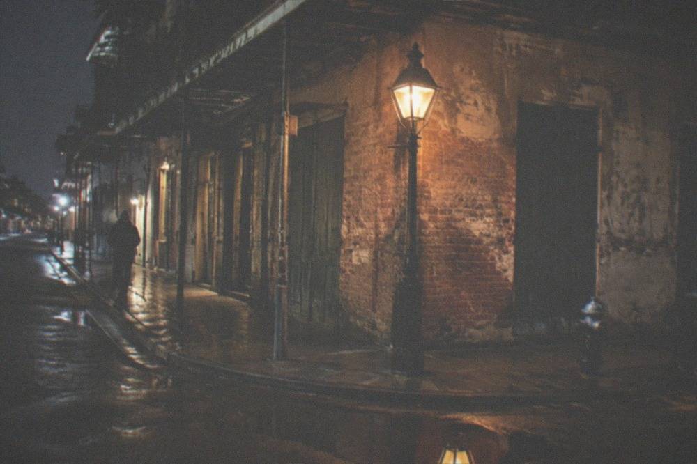 Lantern-lit French Quarter street corner at night with empty sidewalks