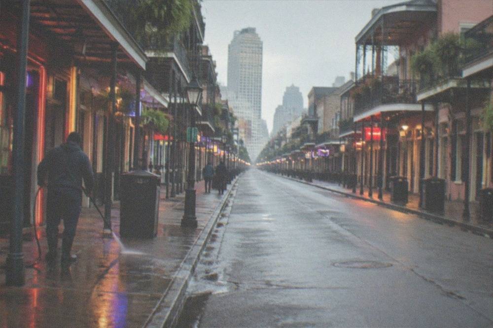 Neon-lit Bourbon Street facades glowing above an empty morning street before the night crowds arrive