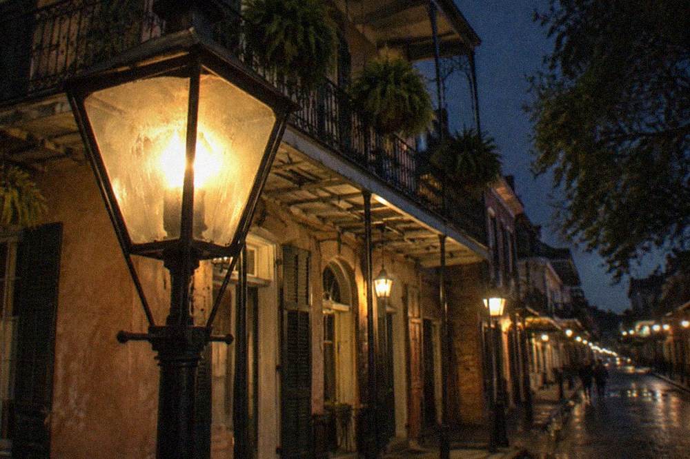Gas style street lamps illuminating a French Quarter corner at night