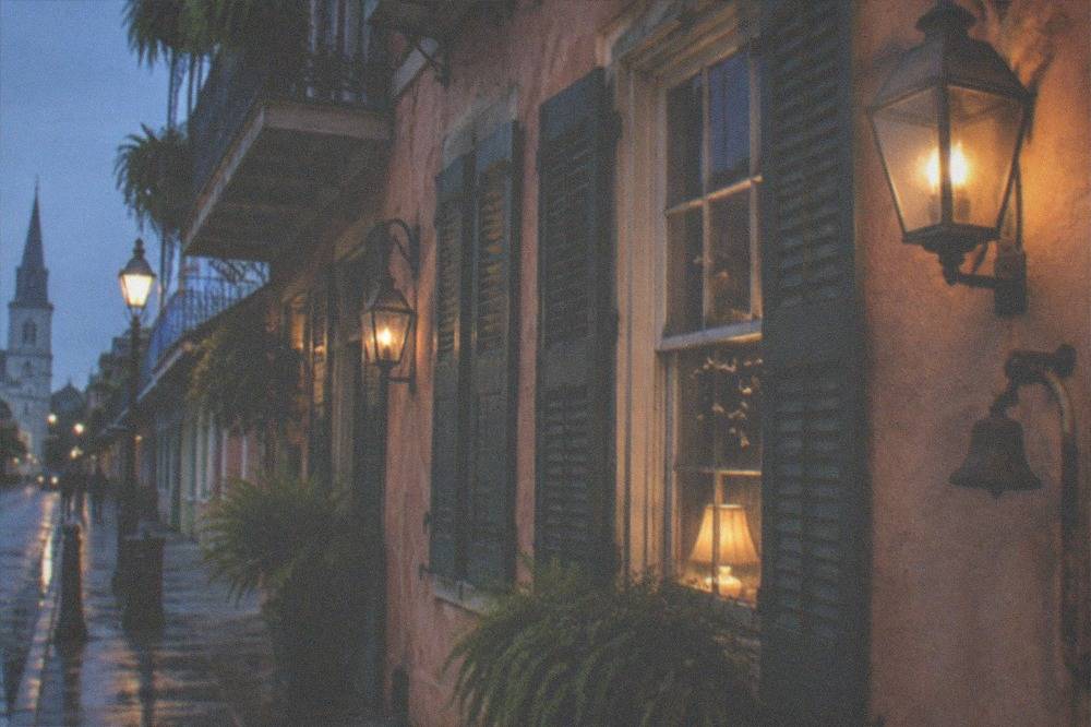 Historic French Quarter building facade lit by evening lamps with shutters