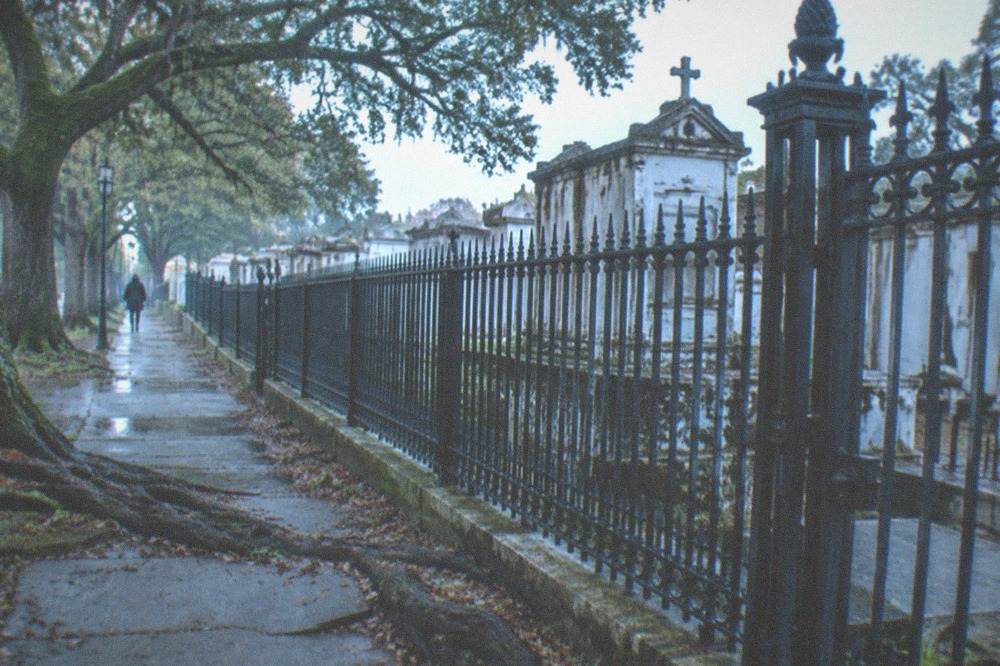 Iron fence and closed gate of a historic cemetery seen from the sidewalk
