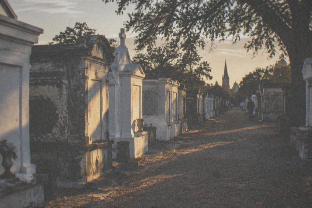 Sunlight falling across rows of white and grey tombs in a New Orleans cemetery