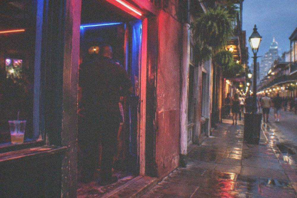 Neon-lit bar entrance on a crowded French Quarter street at night