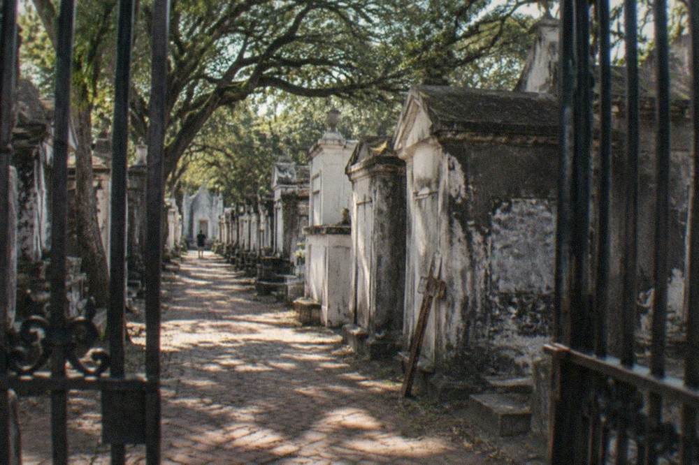 Iron gate and rows of weathered above-ground tombs in a New Orleans cemetery in daylight