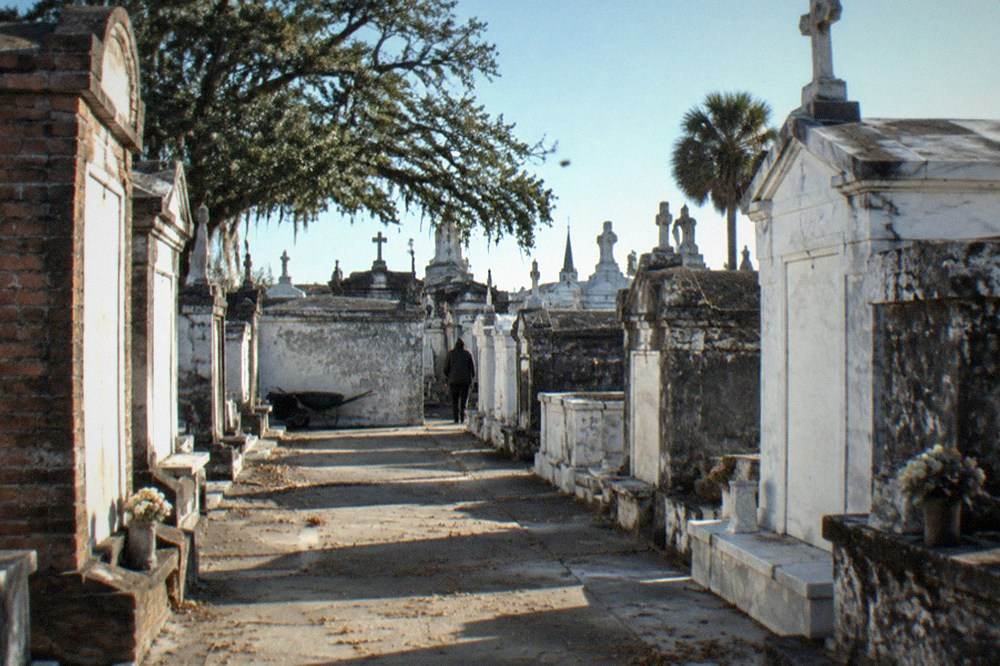 Wide view of sunlit St. Louis Cemetery with rows of brick tombs and clear sky