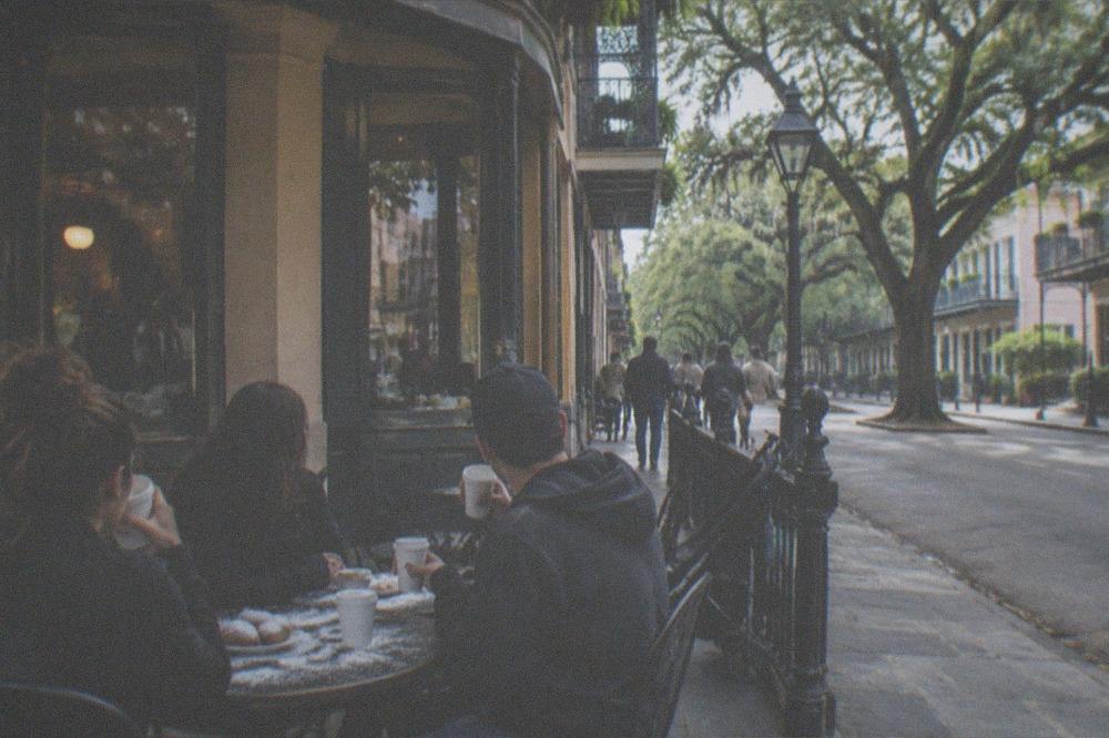 Families and visitors gathered outside a coffee shop meeting point on a New Orleans morning