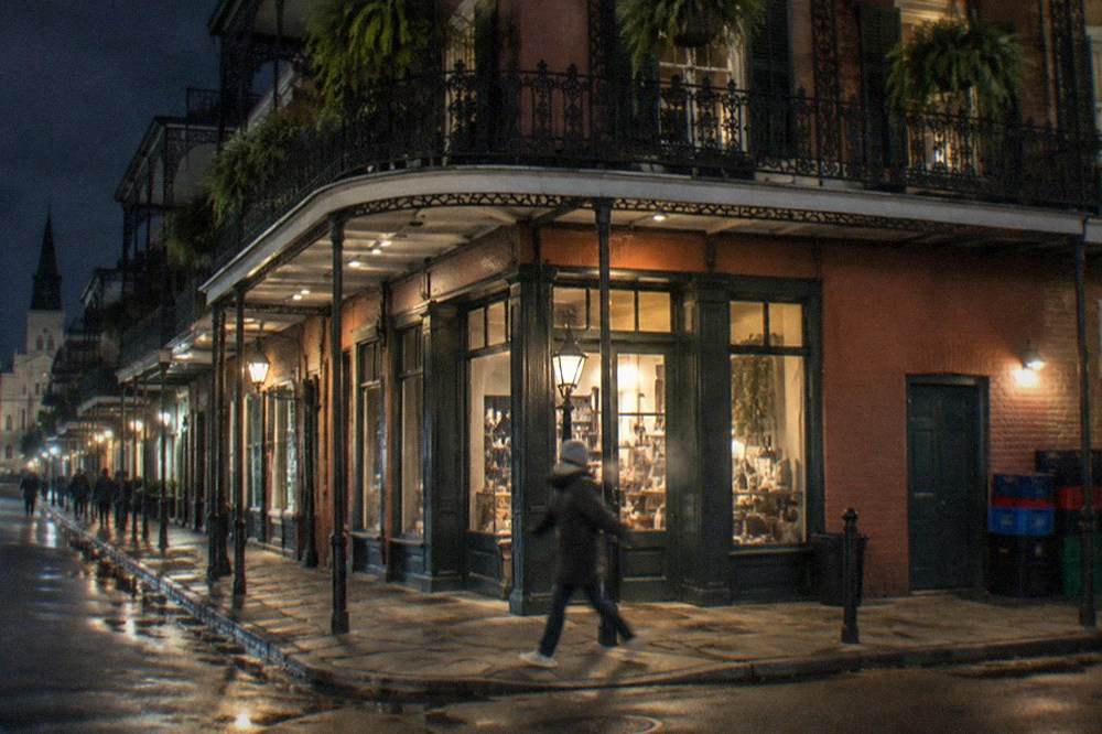 A French Quarter corner building with cast-iron balconies and a lit storefront at night