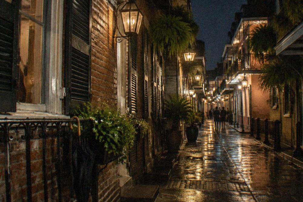 A narrow French Quarter street at night lit by gas lamps with hanging iron lanterns