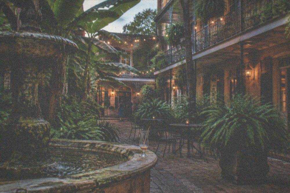 A hotel courtyard in the French Quarter with a stone fountain and tropical plants