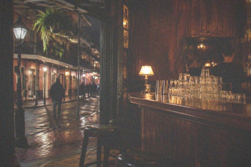 Bartender's counter with stacked glasses and warm lamplight in an old wooden bar