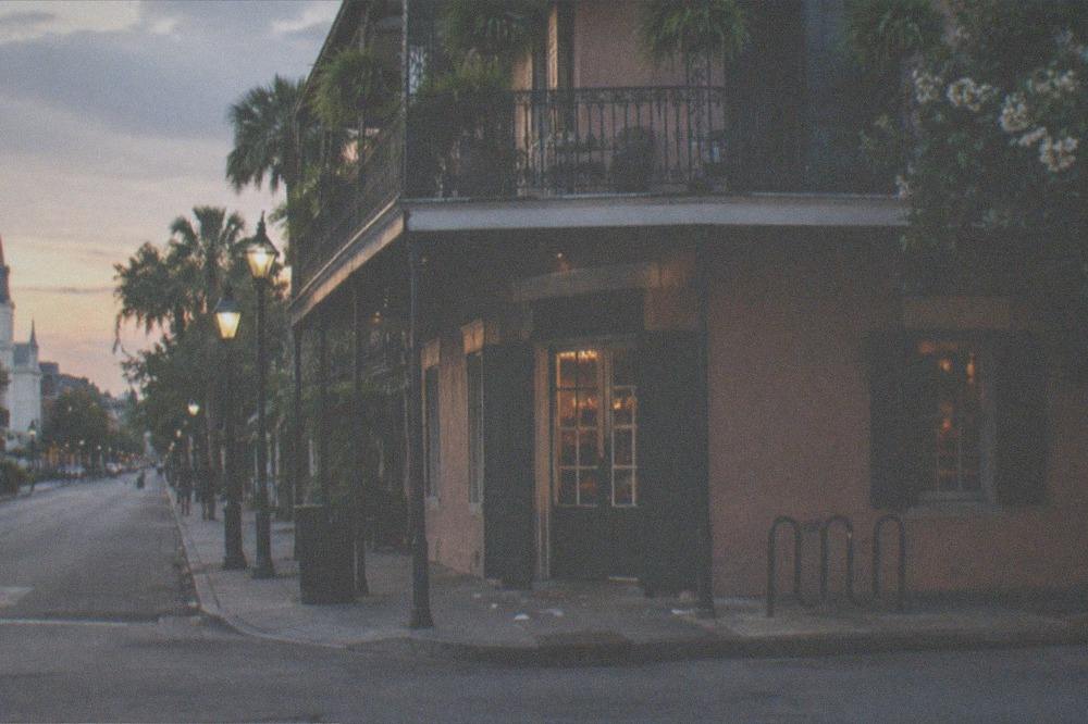 Corner building with iron balcony and glowing sign on a quiet French Quarter corner