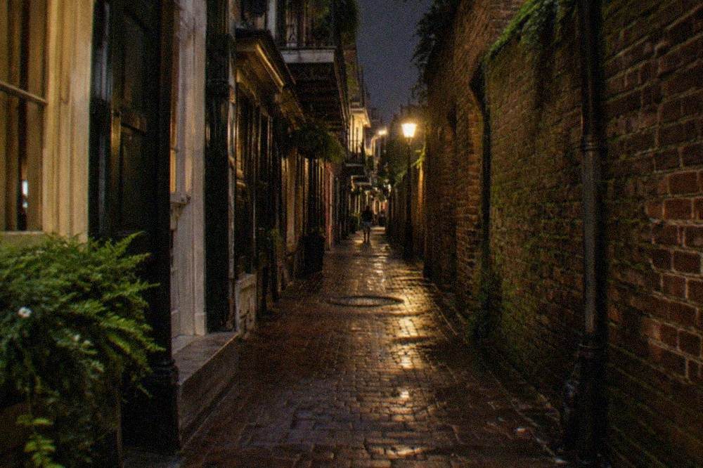 Dark French Quarter alley between old brick buildings at night