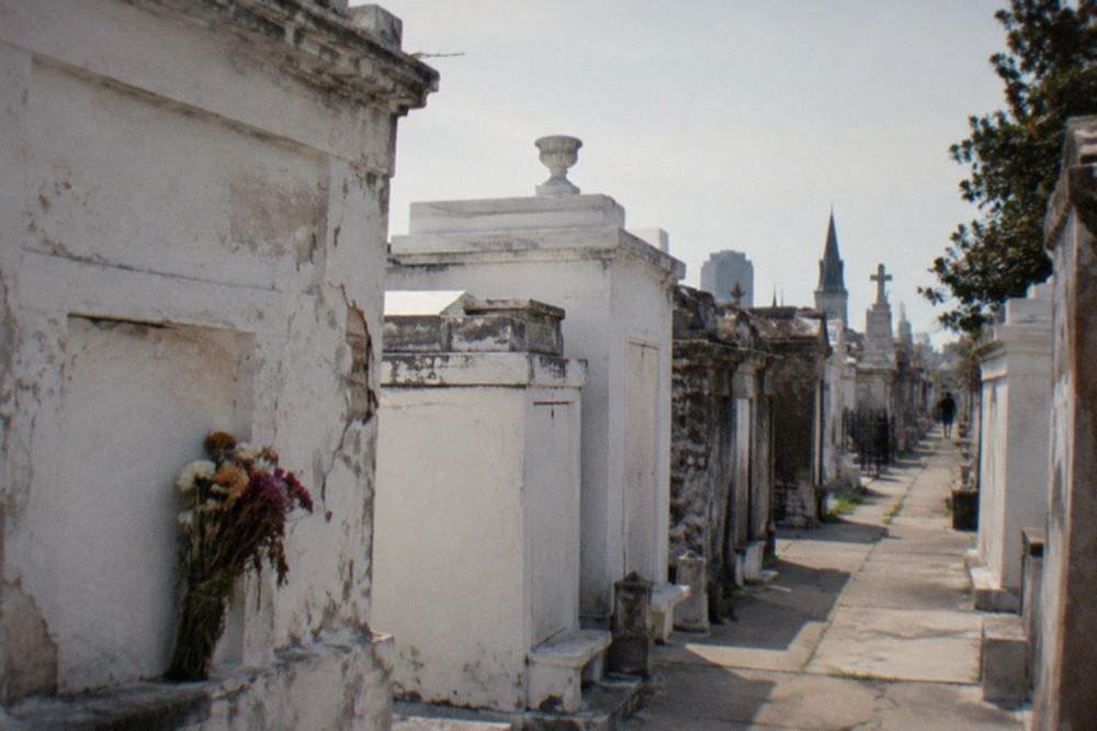 Rows of weathered above-ground tombs painted white under a bright sky in an old New Orleans cemetery
