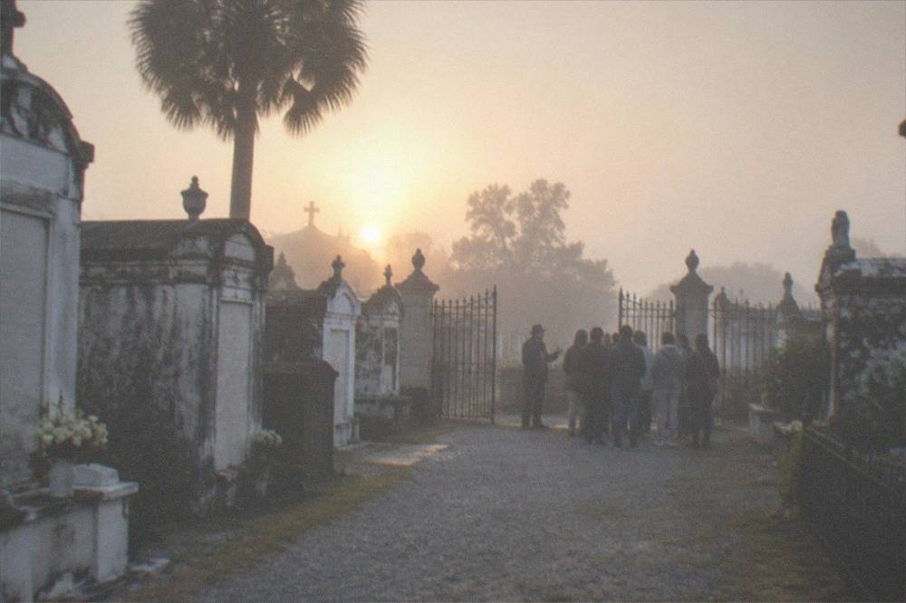Tour group gathered around a licensed guide beside historic cemetery gates in daylight