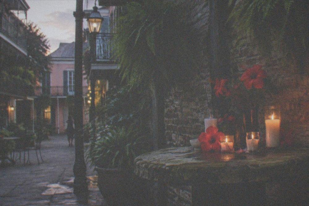 Quiet French Quarter courtyard at dusk with a small altar of candles and flowers