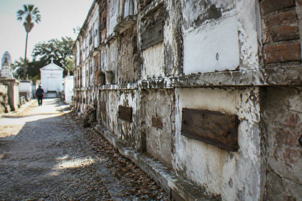 A narrow brick path between weathered white above-ground tombs in the oldest cemetery in New Orleans