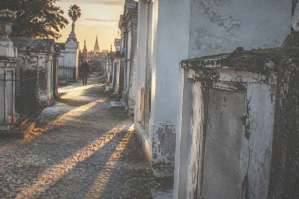 Sunlight falling across rows of faded whitewashed tombs in a historic above-ground cemetery