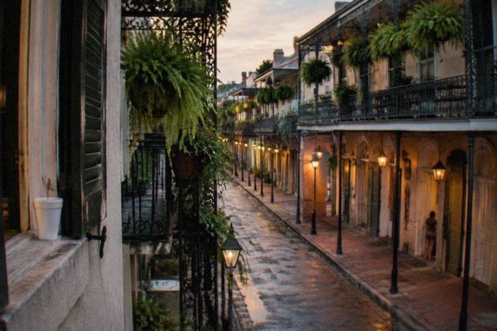 Evening street in the French Quarter with lit signs and ironwork balconies